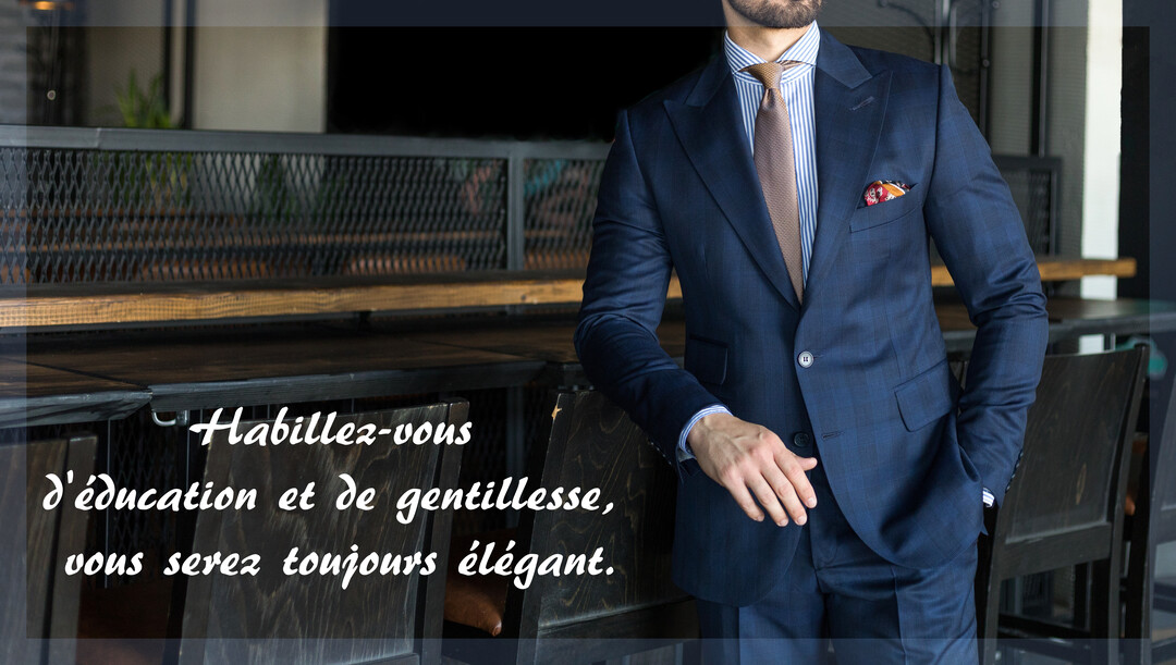 Un homme non identifiable, de torse, porte un élégant costume bleu, une chemise rayée et une cravate, posant dans un décor sobre.