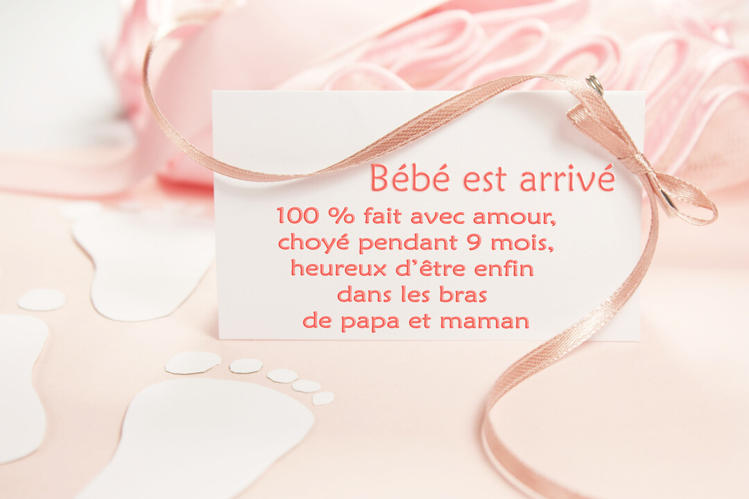 Une carte de naissance blanche posée sur un fond rose, décorée d'un ruban et d'empreintes de pieds, avec un message tendre.