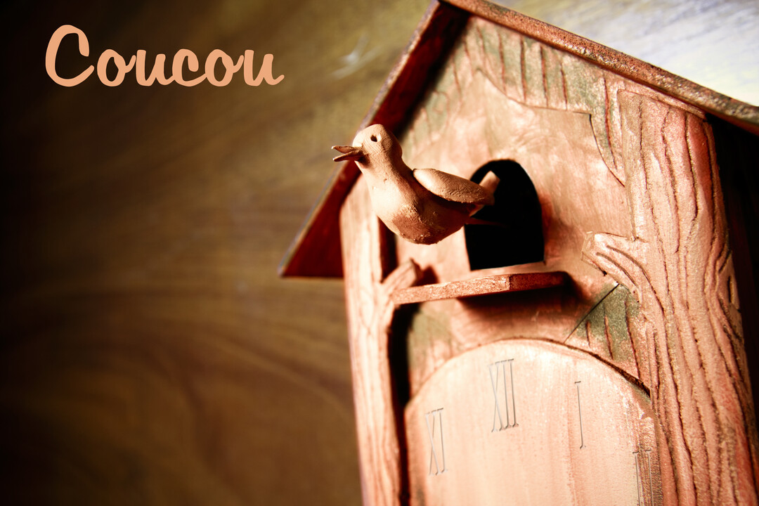Gros plan sur une horloge à coucou traditionnelle en bois, où un petit oiseau sculpté sort de sa niche avec le bec ouvert.